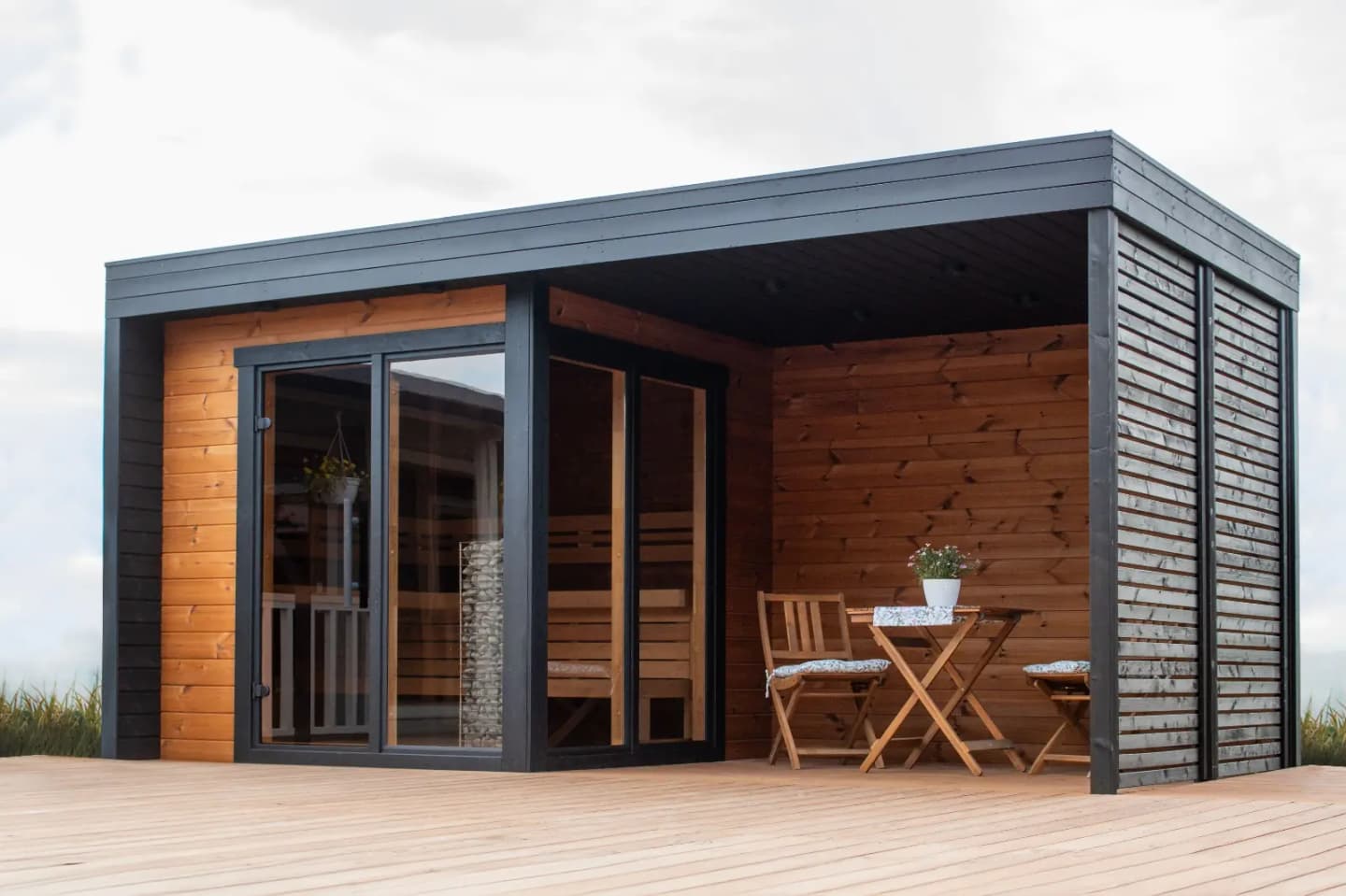 Sauna cabin on a sunlit terrace with a small table and chairs